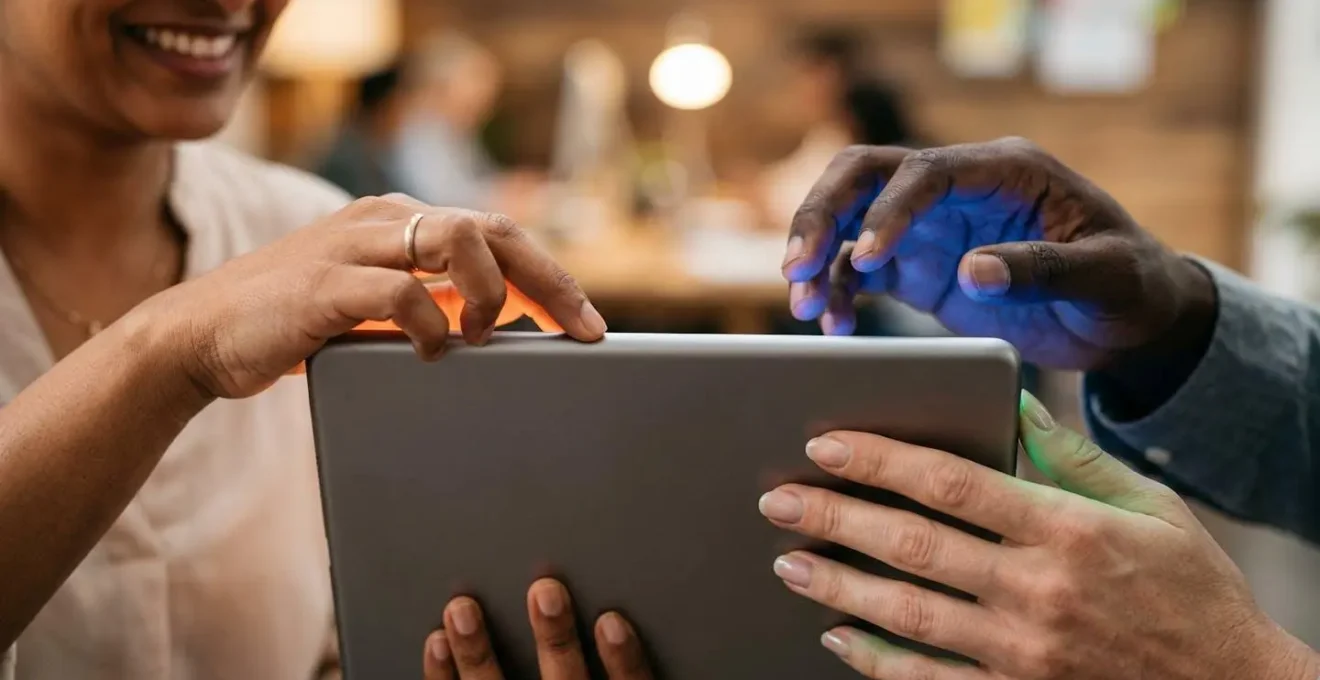 Gros plan sur les mains d'une personne naviguant sur une tablette avec reflets colorés représentant les émotions