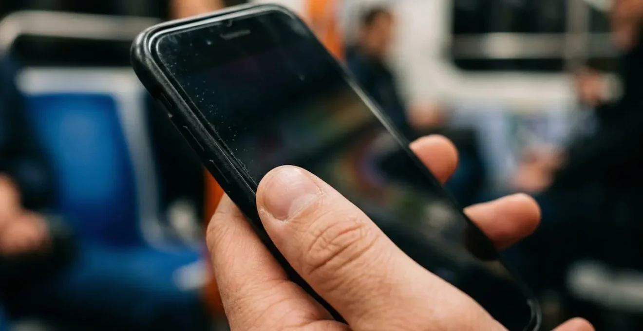 Main tenant un smartphone dans le métro parisien montrant l'ergonomie de la zone du pouce